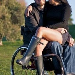 Woman sat in the lap of a man in a wheelchair