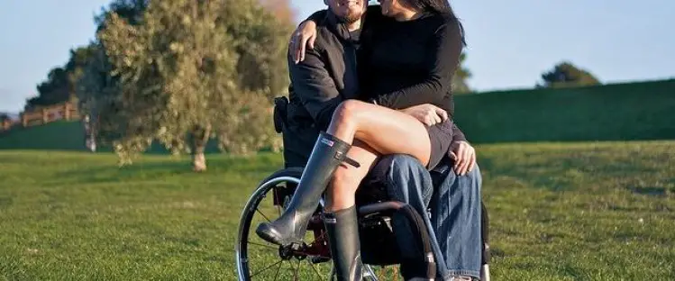 Woman sat in the lap of a man in a wheelchair