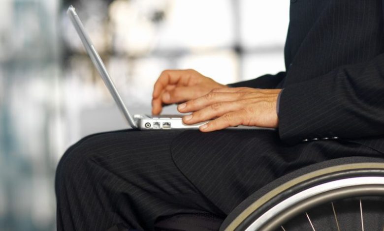 Businessman sitting in a wheelchair working in a laptop