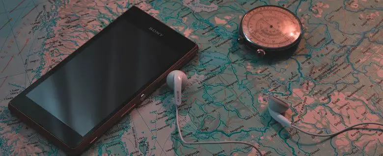 Smartphone laying on map with compass