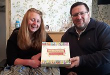 woman iwth long hair and a man with glasses and a beard hold a board game