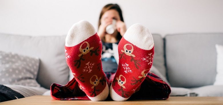 Feet in Christmas socks resting on table