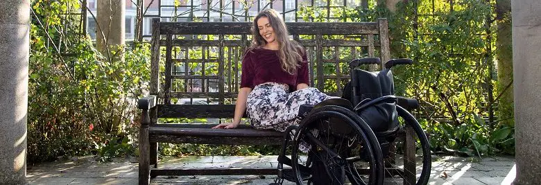 Disabled model Samanta Bullock sat on a bench with legs resting on wheelchair