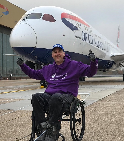 Andy Knight in his wheelchair in front of British Airways plane