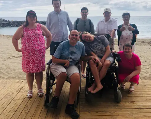 A group of disabled travellers on an accessible beach with Limitless Travel