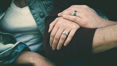 Couple holding hands with wedding rings on