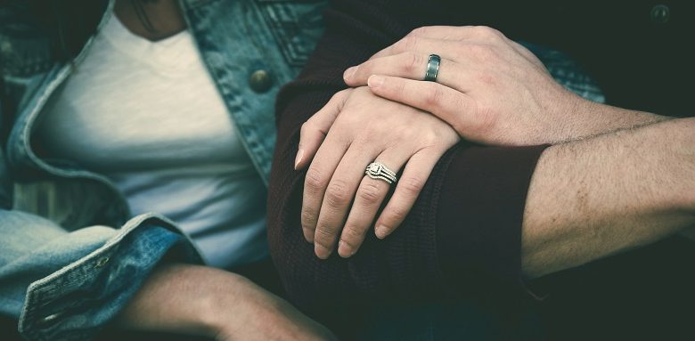 Couple holding hands with wedding rings on