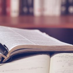 Open books in a library with a pen on top