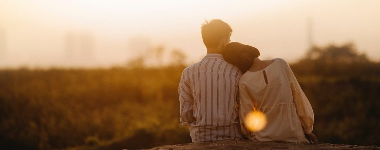 Couple sat in front of a sunset