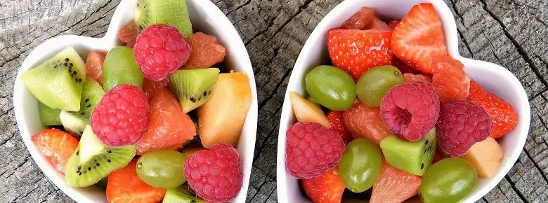 Mixed fruit in two heart-shaped dishes on a wooden table