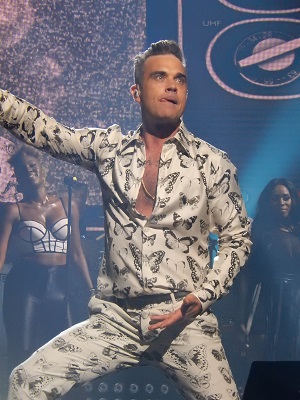 Robbie Williams on stage in a white suit
