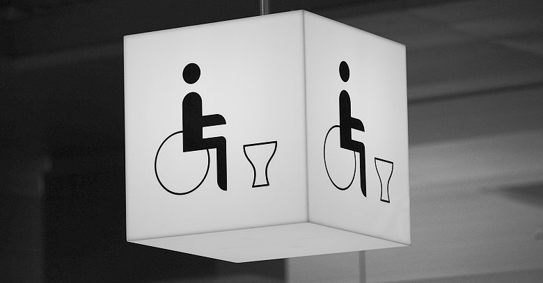 Square disabled toilet sign hanging from the ceiling