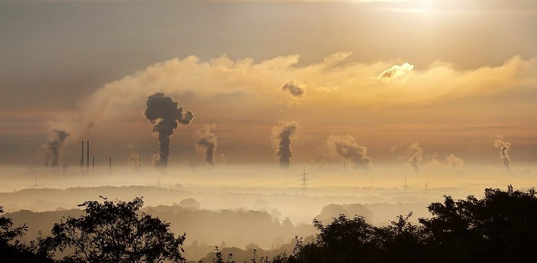 Smoke from factories and electricity pylons against a sunset