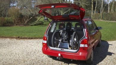 Mountain Trike wheelchair folded into the open boot of a red car