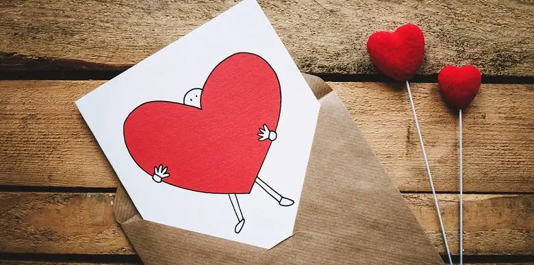 Valentine's Day card one a wooden table with illustration of man holding a red heart