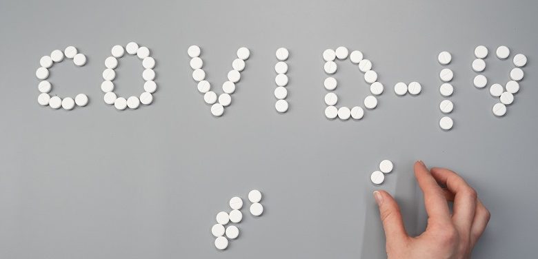 Covid-19 spelt out in pills on a grey background