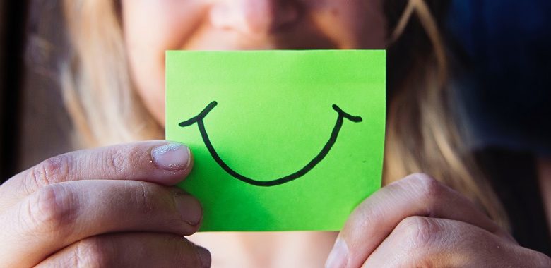 Woman holding green paper with a smile on it