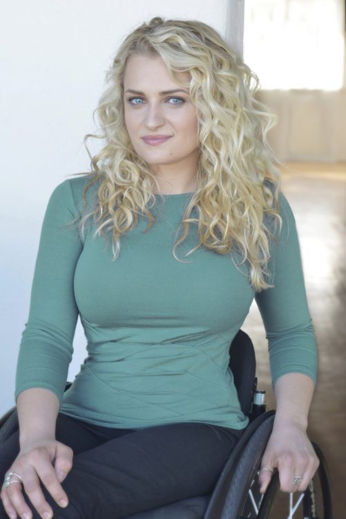 Ali Stroker in her wheelchair in black trousers and a green top