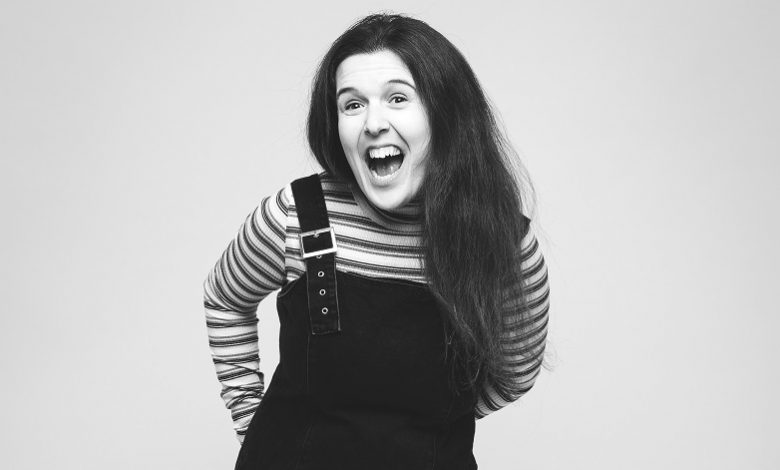 Black and white image of disabled comedian Rosie Jones smiling