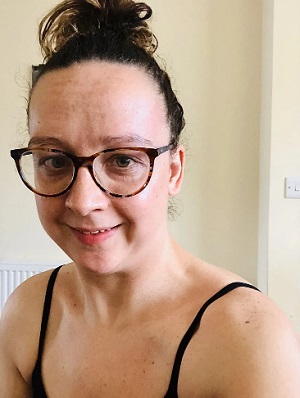 Carrie-Ann after a workout with a black strappy top, glasses and hair tied up