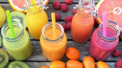Colourful smoothies with straws in a row surrounded by fruit