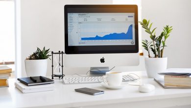 Home office with a Mac computer, plants and coffee cup on a white desk]