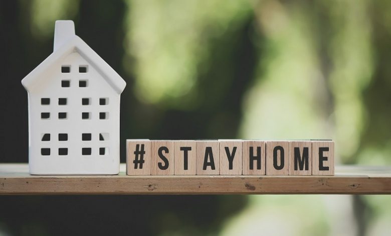 Stay home words spelt out on wooden letter blocks next to a white china house