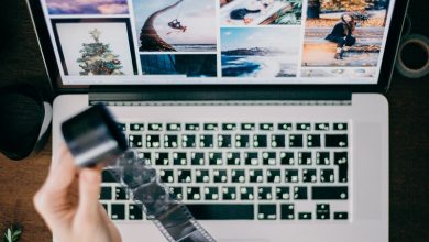 Woman holding a reel of film over a computer with images