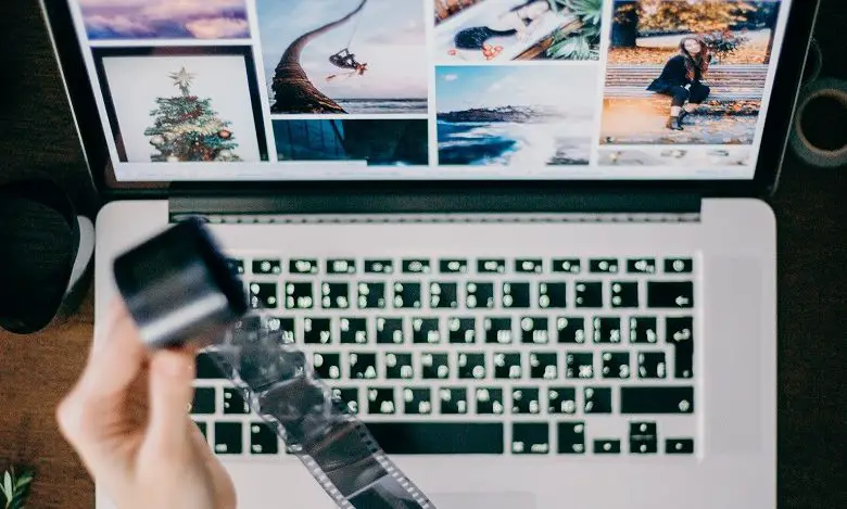 Woman holding a reel of film over a computer with images