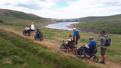 Group of disabled people in all-terrain wheelchairs next to Scar House Reservoir