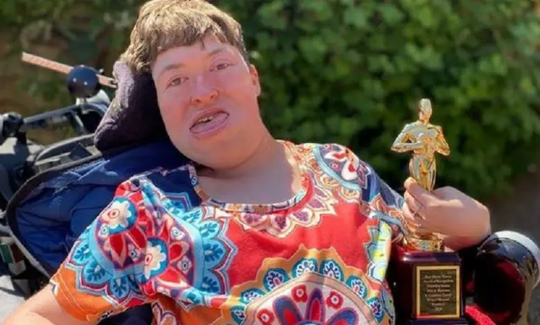 Stephanie-Castelete-Tyrrell-in-her-wheelchair-holding-her-award-in-the-garden