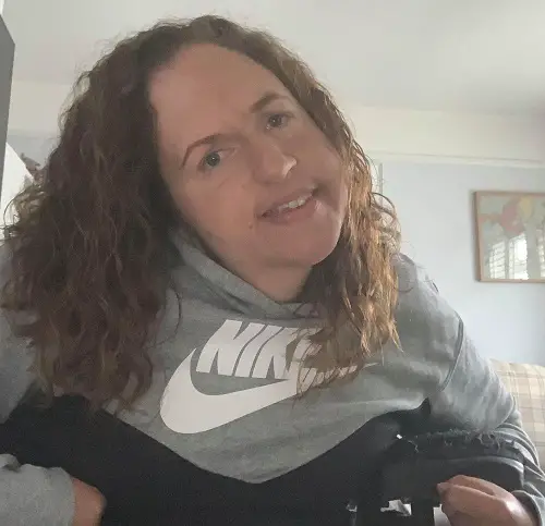 Close up of Georgina Moore in her wheelchair with a grey jumper and brown curly hair