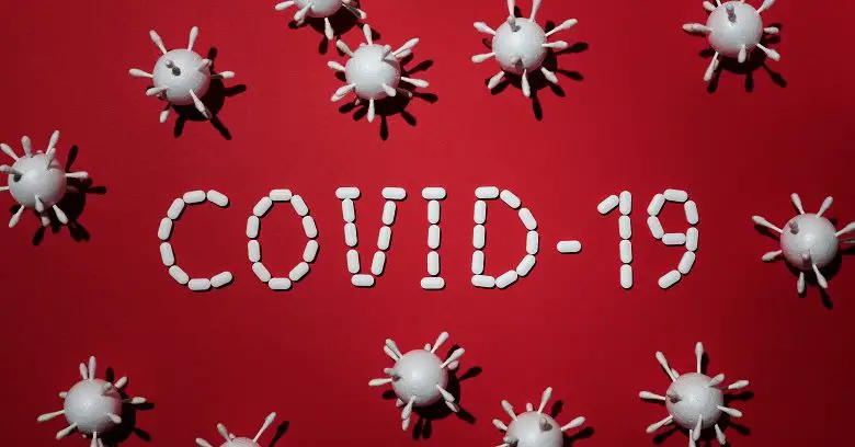 Covid-19 in white words on a red background with images of virus particles around it