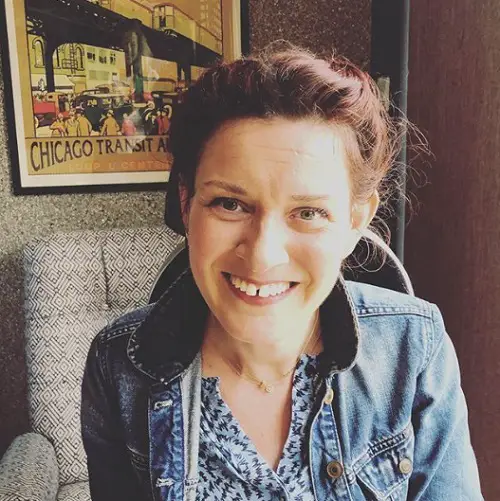 Lucy Reynolds in a cafe wearing a denim jacket and blue top with her hair up