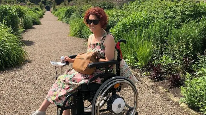 Lucy Reynolds in her wheelchair in a floral dress in a large garden