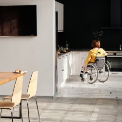 Open plan dinning room and white kitchen with a woman in a wheelchair