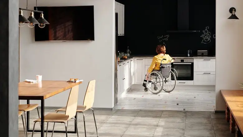 Open plan dinning room and white kitchen with a woman in a wheelchair