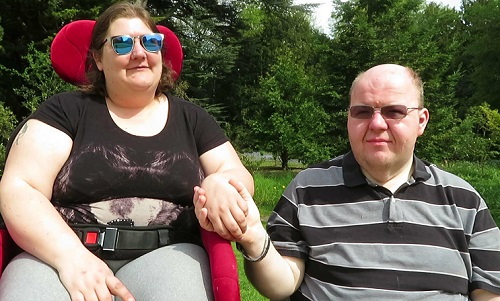 Stacey Kovaciny in her wheelchair holding hands with her partner