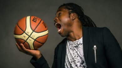 Ade Adepitan holding a basketball as if he is going to eat it