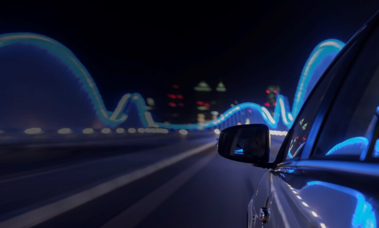 Side of a car driving at night with lights reflected on it