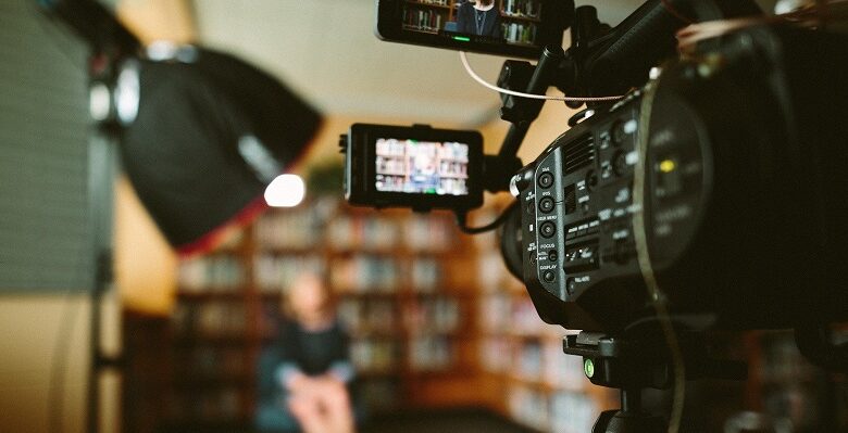 View from behind a camera filming a woman sat in a library