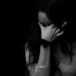 Black and white image of a woman with black hair holding her face in her hand