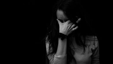 Black and white image of a woman with black hair holding her face in her hand