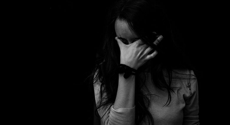 Black and white image of a woman with black hair holding her face in her hand