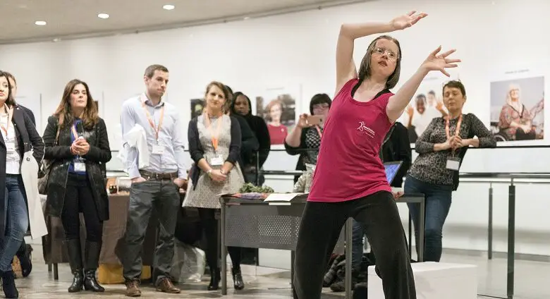 Jan in a pink top dancing in front of a group of people