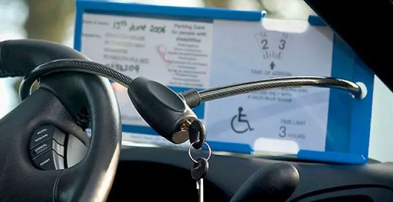 The Blue Badge Protector anti-theft device being used in a car around a steering wheel and Blue Badge Holder