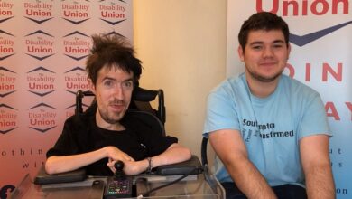 George Baker and Joel sat in front of logos for The Disability Union
