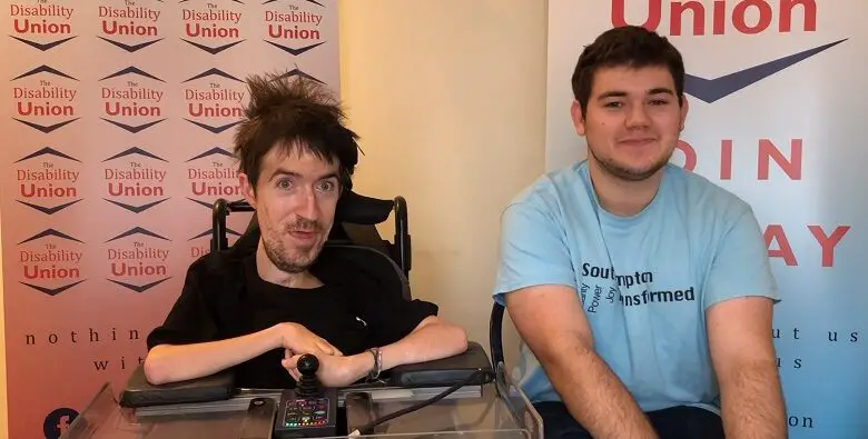 George Baker and Joel sat in front of logos for The Disability Union