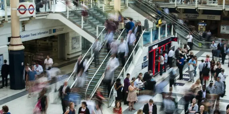 Stairs and an escalator at Liverpool railway station very busy with lots of people walking around it blurred as they're walking fast