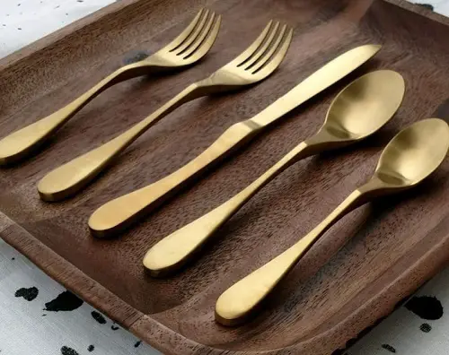 Satin brass Knork knife and fork 5-piece cutlery set on a wooden board - kitchen aids for disabled